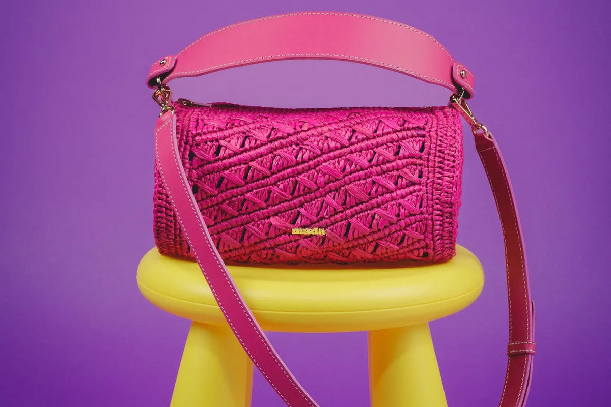 sac bowling mada en raphia rose avec anses en cuir, posé sur un tabouret jaune